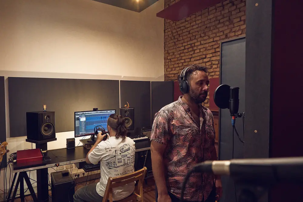 Adrián grabando una voz mientras Joaquín opera la sesión