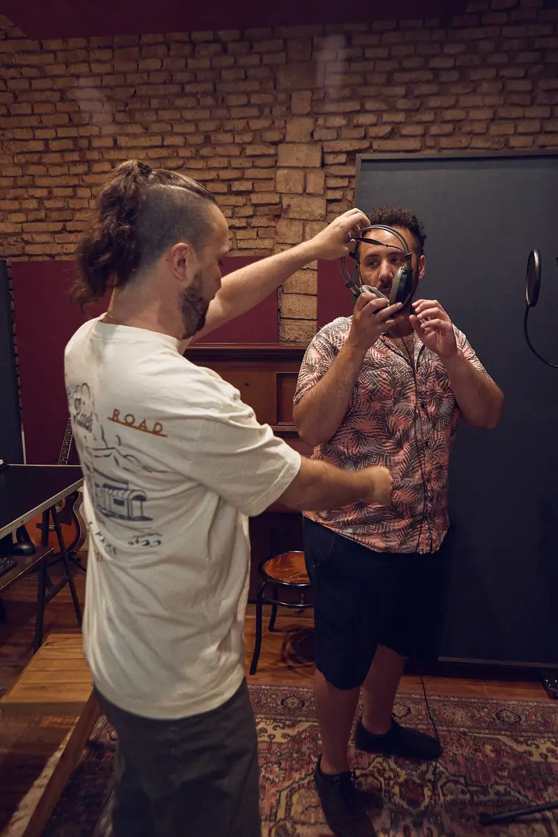 Joaquín ayudando a Adrián a acomodarse los auriculares antes de grabar